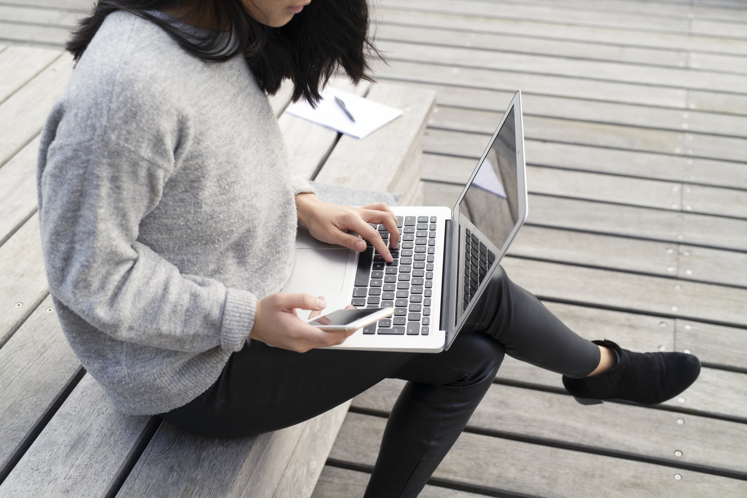 dame med mobil i hånden og laptop i fanget